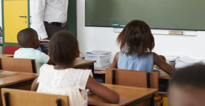 Teacher at chalkboard in elementary school class, vertical